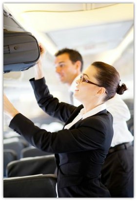 Flight attendant helping to store a carry on bag on a flight.